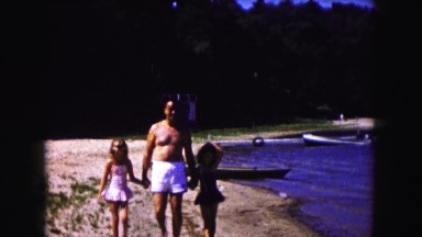 1961: a man walks with his daughters on the beach. MINNESOTA