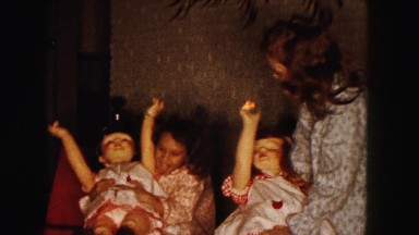 1961: two girls in robes wrestle with life-size dolls to make them sit or stand