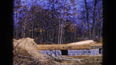 1954: man woman and child walking towards cinder block foundation of new home