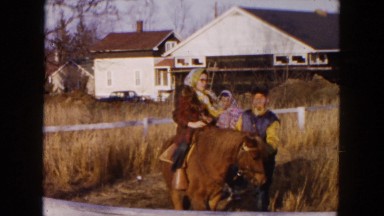 1954: a woman and a child riding separate horses around a fence HICKSVILLE