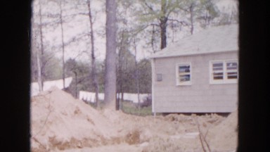 1954: small child and woman walking by newly built house and dirt pile
