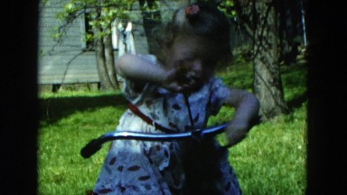 1954: young girl trying to fix the handlebars on her bicycle with a screwdriver