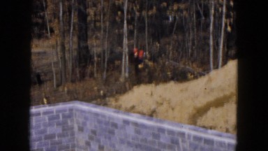 1954: woman wearing a stole carrying a child uphill into the woods. HICKSVILLE