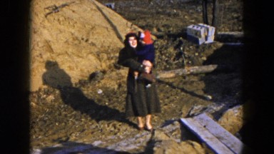1954: a woman outdoor in a coat holding a small toddler in her arms HICKSVILLE