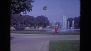1972: Woman in Red Jacket Standing in Front of Large Pond