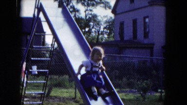 1954: Little Girl Scooting Down Slide Into Daddy's Arms in Backyard