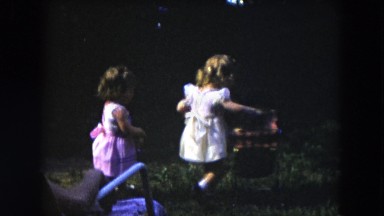 1954: two young girls playing with a baby doll and baby doll carriage