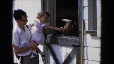1954: man and young child petting barnyard animal HICKSVILLE, NEW YORK