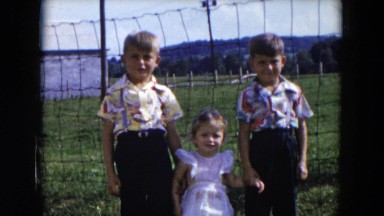 1954: two cute little boys and a little girl posing in front of a fence