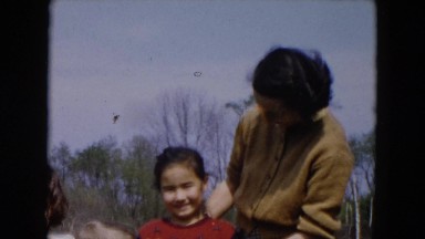 1955: a lady with three children are posing the lady is fixing a girl's hair