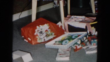 1955: gift building with family on floor surrounded by many opened boxes
