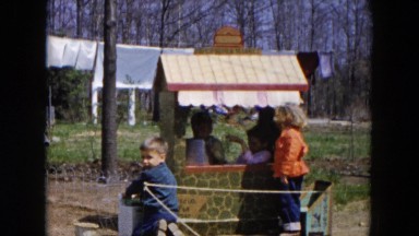 1955: children playing outdoor in the sun around what looks like a lemonade