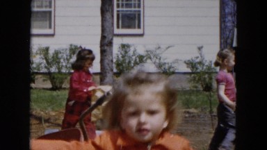 1955: several children jumping and playing in a large courtyard in a rural area