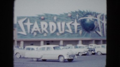 1958: fifties car sit in a parking lot outdoor a hotel that has a huge sign
