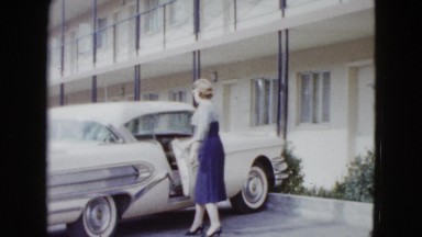 1958: a lady wearing a blue and white dress gets into a car