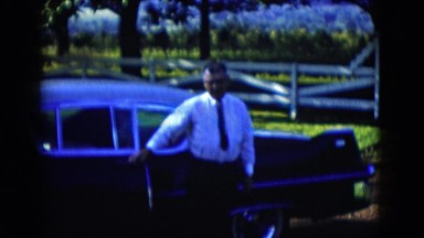 1958: a man in a tie exits a car closes the door and walks casually