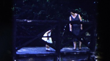 1955: a woman and a little girl in a dress standing on a wooden platform or dock
