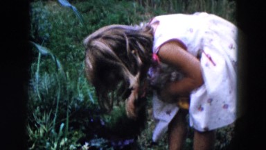 1955: a little girl fighting hard for removing leaves from some carrots
