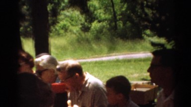 1964: friends and family gather at an outdoor picnic at a table in the shade