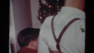 1964: a man in suspenders and a boy stand in front of a christmas tree