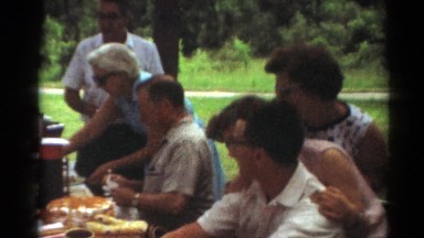 1964: people sitting casually at a picnic table in a park eating lunch