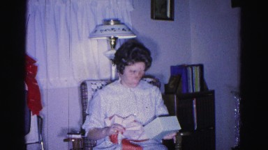1967: a woman dressed in a nightgown opens a christmas present