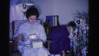 1967: a family in pajamas opening gifts from under a decorated christmas tree