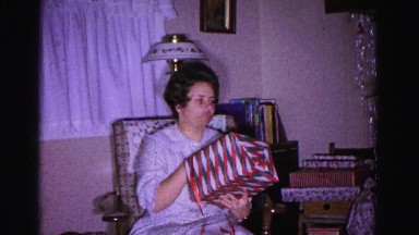 1967: woman sitting in rocking chair, unwrapping gift HAGERSTOWN, MARYLAND