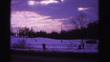 1967: a winter view of people skiing down a hill set against a grove of trees