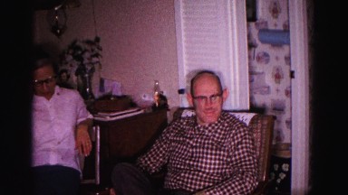 1967: an elderly couple is seated near a christmas tree decorated with tinsel