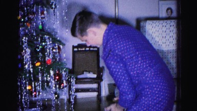 1967: young boy working to open a gift on christmas morning HAGERSTOWN, MARYLAND