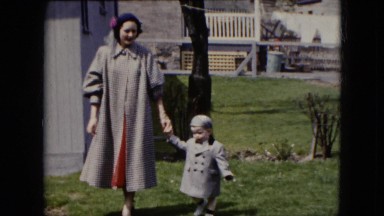 1951: beautiful mother and her cute child walking on the meadow CLEVELAND, OHIO