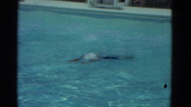 1953: swimwear splashing through a butterfly stroke in clear blue water