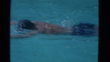 1953: a boy jumps into a swimming pool and crosses swimming from one side