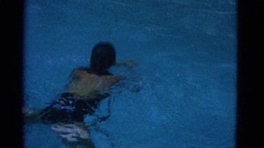 1953: a young lady in a bathing suit swimming through a crystal clear pool