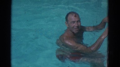 1953: Man in Red Swim Trunks Talking to Camera in Swimming Pool New York