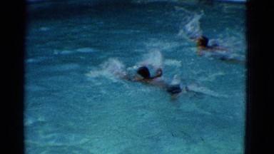 1953: swimming race among school-aged boys in a pool doing the butterfly stroke