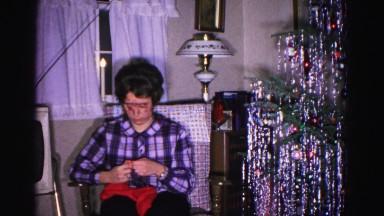 1967: woman unwraps small christmas present while talking to someone off camera