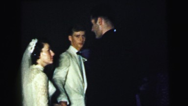 1964: A Young Newly Married Couple Talking to a Priest During a Wedding Feast in Camden