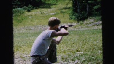 1964: a young blond man taking shots with a rifle in a rural area CAMDEN