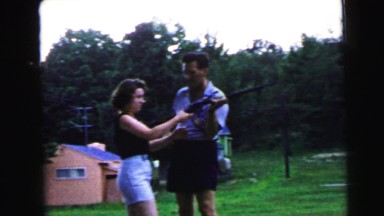 1964: a man outdoors teaching a young woman how to fire a gun CAMDEN, NEW JERSEY