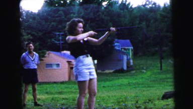 1964: a woman is shooting with a rifle while is being observed by a man CAMDEN
