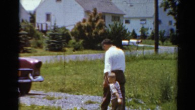 1964: a father holds his boy's hand and walks him to a car in the driveway