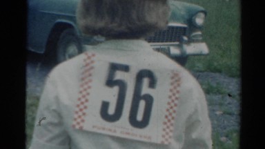 1964: a woman with the number fifty-six on her back walking to a car CALIFORNIA