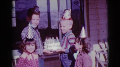 1968: two boys are holding a birthday cake with candles on the front porch