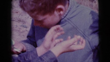 1968: a cute young boy outdoors, looking for easter eggs in the bush