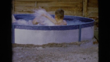1968: two rambunctious boys wrestling and playing in a small swimming pool