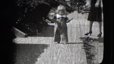 1942: a toddler eating ice-cream outdoor walking next to his mother in heels.