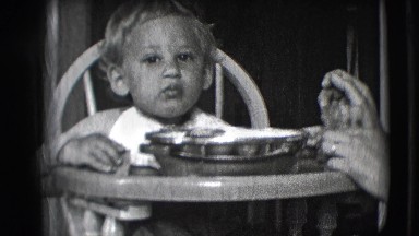 1942: small child being fed in a highchair NEW YORK