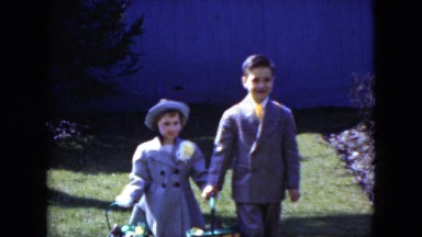 1951: A Well-Dressed Boy and Girl Walking Through the Grass Carrying Easter Egg Baskets